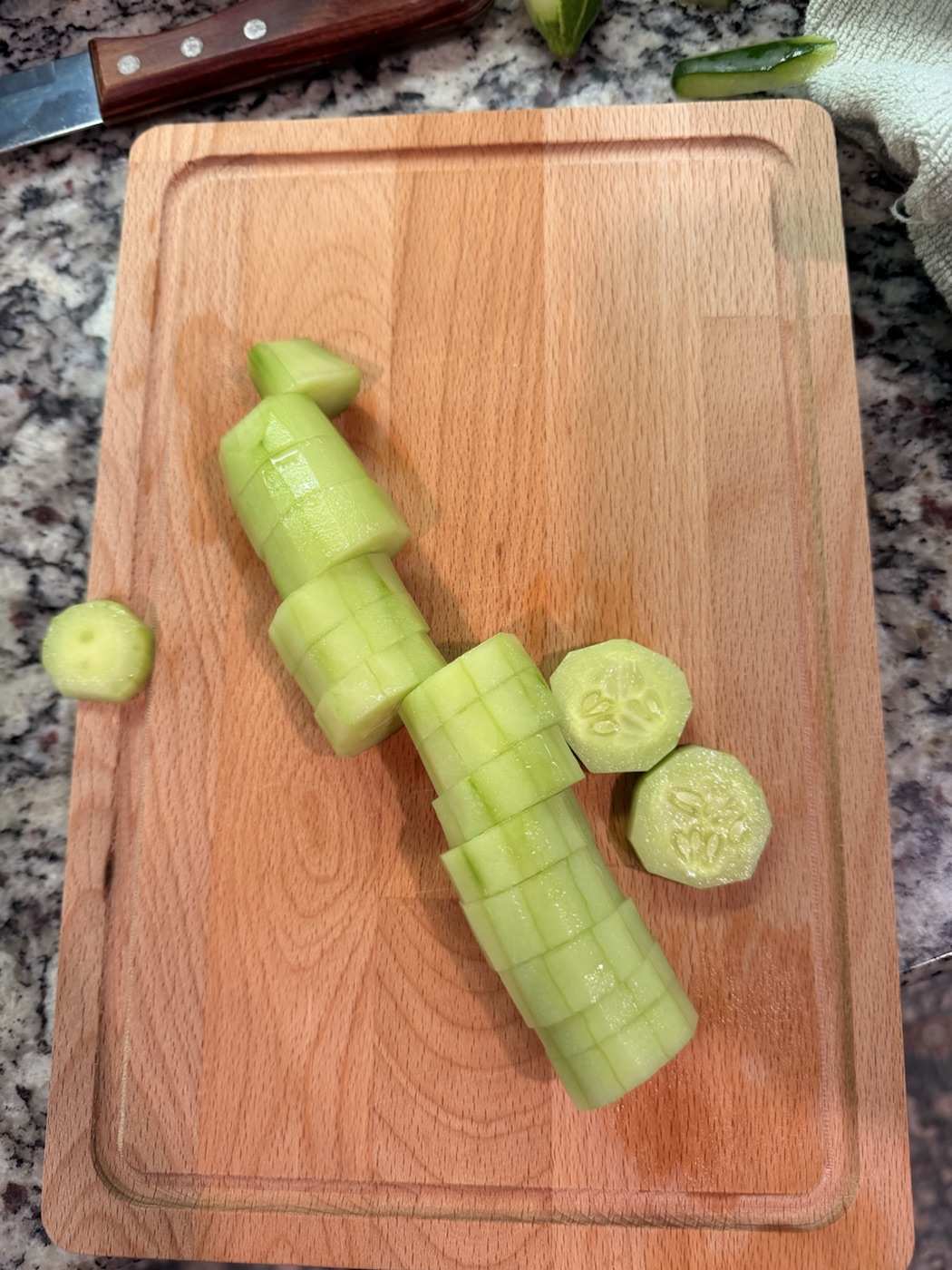 Fresh cucumbers being prepared on a wooden cutting board